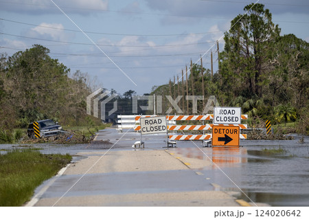 Road closed for roadworks and danger of flooding with warning signs blocking driving of cars Road closed for roadworks and danger of flooding with warning signs blocking driving of cars 124020642