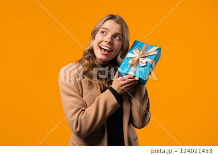Happy stylish businesswoman gift box, yellow background. Lady smiling,interested Happy stylish businesswoman gift box, yellow background. Lady smiling,interested 124021453