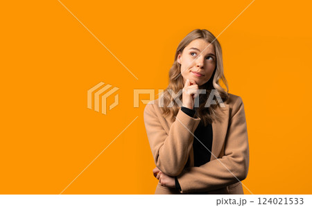 Thinking around stylish businesswoman on yellow background. Puzzled lady looking answer. Copy space. 124021533