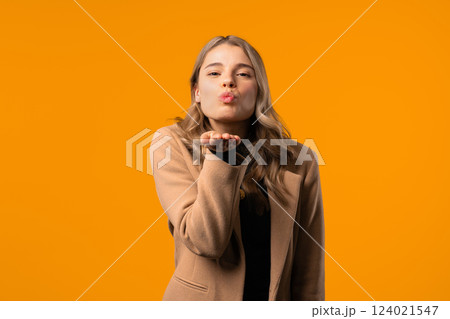 Smiling Coquette Woman Sending Air Kiss, Flirt To Camera On Yellow Background Smiling Coquette Woman Sending Air Kiss, Flirt To Camera On Yellow Background 124021547