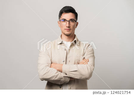 Unstoppable confidence. A man in eyeglasses and a beige overshirt standing with arms crossed, exuding self-assurance. A perfect blend of intellect and bold style Unstoppable confidence. A man in eyeglasses and a beige overshirt standing with arms crossed, exuding self-assurance. A perfect blend of intellect and bold style 124021754