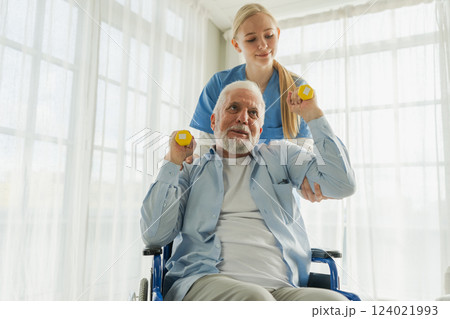 Support rehabilitation healthcare. Nurse helps old man patient in wheelchair picking up dumbbells. Paralyzed man in chair for people with disability doing sports exercise with nurse. Medical caregiver Support rehabilitation healthcare. Nurse helps old man patient in wheelchair picking up dumbbells. Paralyzed man in chair for people with disability doing sports exercise with nurse. Medical caregiver 124021993