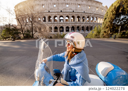 Stylish Italian Woman Riding a Scooter in Front of the Colosseum in Rome 124022278