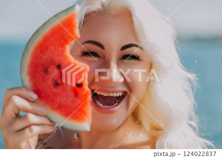 Woman Watermelon Summer Beach: Joyful portrait, woman playfully holding watermelon slice near ocean, summer fun. 124022837