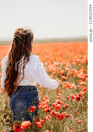 Woman poppies field. Side view of a happy woman with long hair in a poppy field and enjoying the beauty of nature in a warm summer day. 124022854