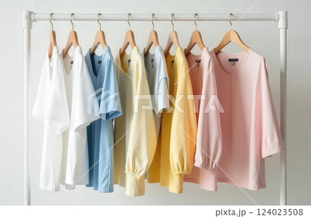 A minimalism clothing rack with pastel and neutral garments in white, blue, yellow, and pink shades 124023508