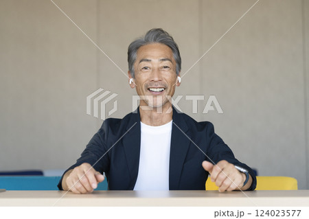 カメラ目線で話すイヤホンをした60代の男性 124023577