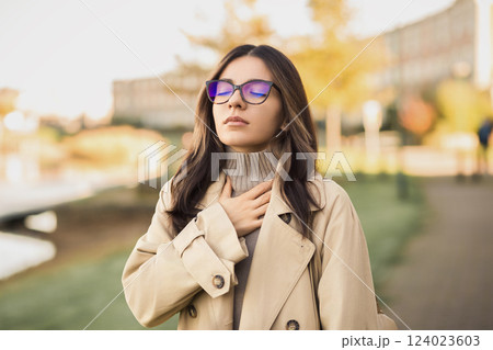 Spring is not always refreshing. A young woman struggles to breathe on a busy street, overwhelmed by seasonal allergies or urban pollution 124023603