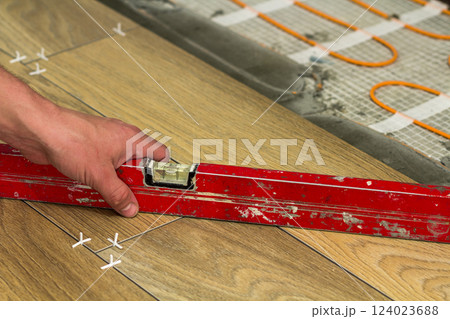 Installation of ceramic tiles and heating elements in warm tile floor. Renovation and improvement concept. Installation of ceramic tiles and heating elements in warm tile floor. Renovation and improvement concept. 124023688