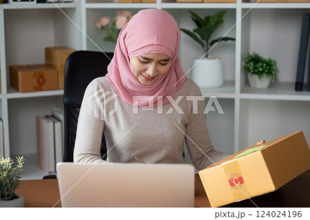 Muslim woman managing online sales and packaging orders at her home office. 124024196