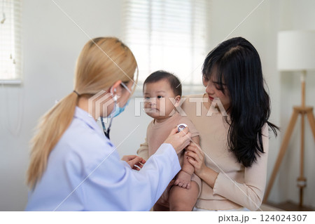 Pediatrician examining baby with stethoscope while mother observes attentively. Pediatrician examining baby with stethoscope while mother observes attentively. 124024307