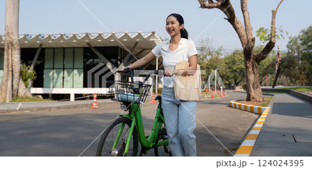 Cheerful woman with bicycle in a sunny urban setting, advocating for eco-friendly commuting. 124024395