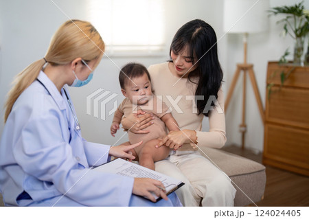 Pediatrician examining baby with parent during a health consultation Pediatrician examining baby with parent during a health consultation 124024405