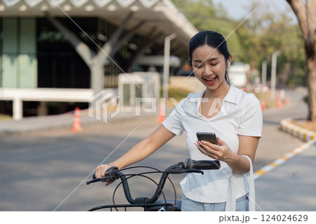Eco-friendly commuting. Young woman checking her phone while beside her bicycle. Eco-friendly commuting. Young woman checking her phone while beside her bicycle. 124024629