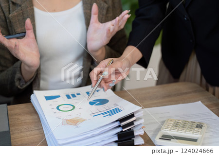 Collaborative analysis. Professionals discussing financial data and tax strategies at a desk during a meeting. Collaborative analysis. Professionals discussing financial data and tax strategies at a desk during a meeting. 124024666