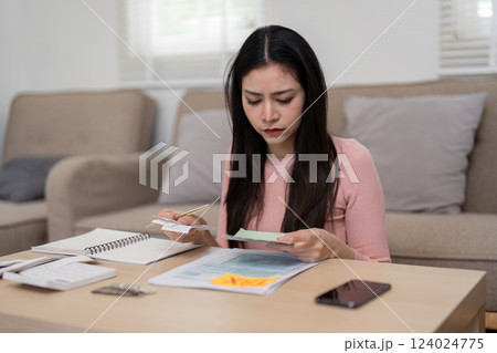 Woman reviewing financial documents for tax preparation at home. Woman reviewing financial documents for tax preparation at home. 124024775