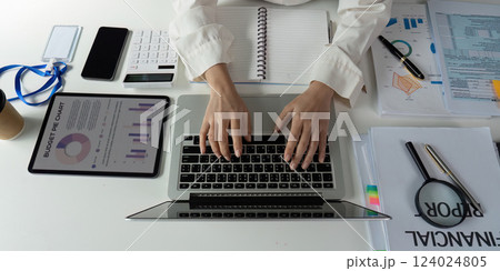 Professional accountant preparing financial reports and analyzing budget data at a modern workspace. 124024805
