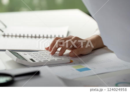Tax calculation. Close-up of a hand calculating financial numbers with a calculator. 124024958