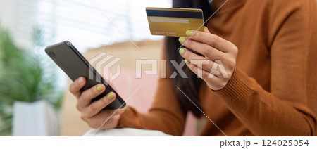 Digital shopping delight. Woman engaged in online shopping with laptop and credit card in her stylish living room. 124025054