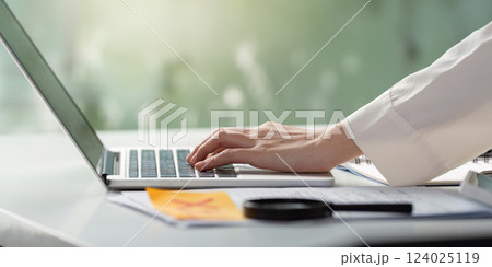 Detail of a hand pointing at tax forms while reviewing financial documents on a desk. Detail of a hand pointing at tax forms while reviewing financial documents on a desk. 124025119