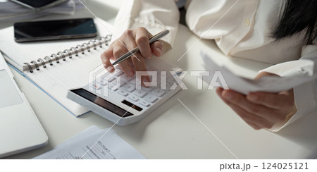 Tax Analysis. An individual conducting financial calculations and organizing tax documents at a desk with a calculator and notepad. Tax Analysis. An individual conducting financial calculations and organizing tax documents at a desk with a calculator and notepad. 124025121