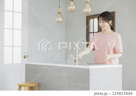 キッチンで水を飲む女性   124025684