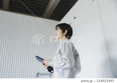 工場でタブレットを持って立っている若い女性 124025943
