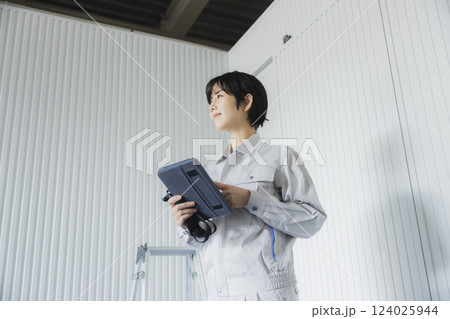 工場でタブレットを持って立っている若い女性 124025944