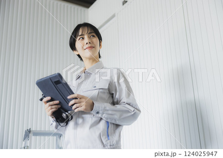 工場でタブレットを持って立っている若い女性 124025947
