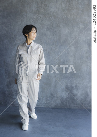 倉庫内を歩く作業着姿の女性 倉庫内を歩く作業着姿の女性 124025992