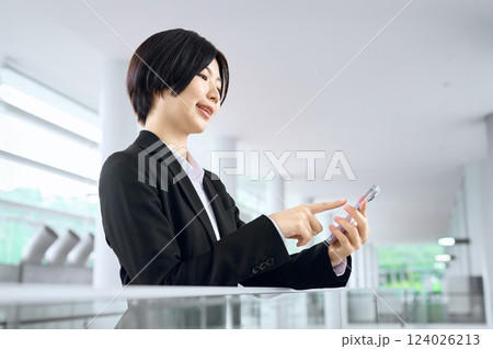 オフィスでスマホを見るスーツのビジネスウーマン 124026213