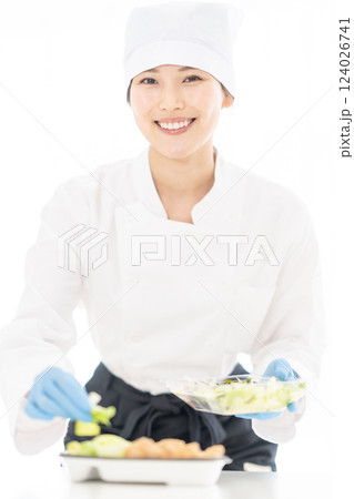 食品工場で御惣菜を詰める若い女性 食品工場で御惣菜を詰める若い女性 124026741