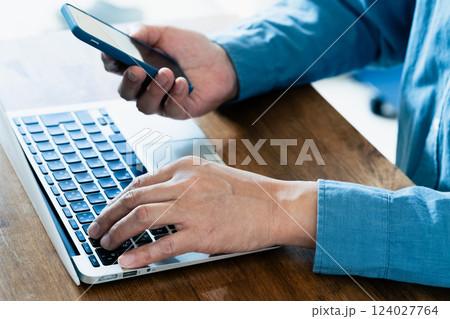 スマホとパソコンを操作する男性 124027764