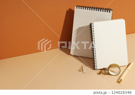 Open notebooks stand with pens on a light background 124028346