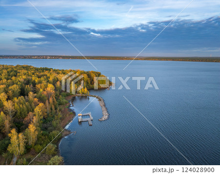 Autumn forest on lake shore at sunset and city on horizon, auerial view 124028900