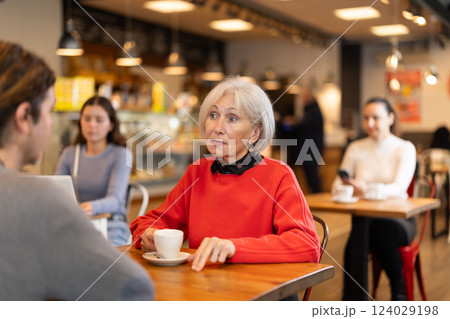 Elderly woman meets a man in a cafe. Conversation over cup of coffee Elderly woman meets a man in a cafe. Conversation over cup of coffee 124029198