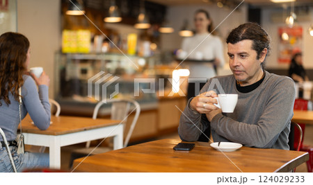 Man whiles away time and waits for meeting in chain cafe 124029233