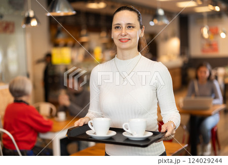Woman visitor in self-service cafeteria carries tray with two cups of coffee. Woman visitor in self-service cafeteria carries tray with two cups of coffee. 124029244