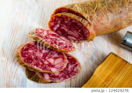 Spanish salchichon sausage cut in slices on a wooden surface Spanish salchichon sausage cut in slices on a wooden surface 124029276