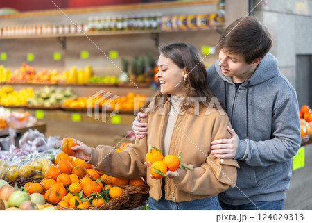 Young woman and young guy choose tangerines Young woman and young guy choose tangerines 124029313