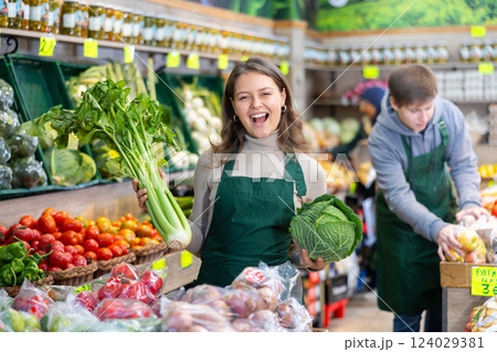 Positive girl seller with cabbage in her hands in the grocery department of supermarket Positive girl seller with cabbage in her hands in the grocery department of supermarket 124029381