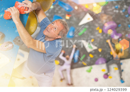 Adult man practicing rock climbing on climbing wall Adult man practicing rock climbing on climbing wall 124029399