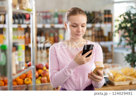 Female buyer scans QR code on cheese label in grocery store 124029491