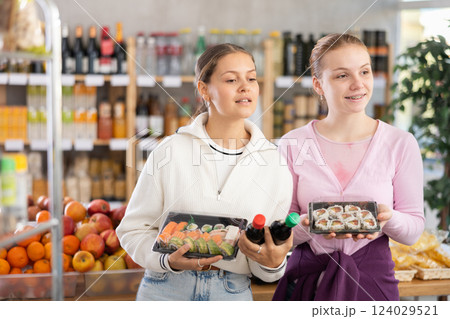 Young women choose sushi and sauces for them 124029521