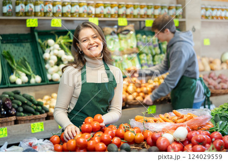 Young woman seller lays out tomatoes on counter 124029559