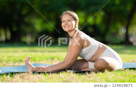 Girl enjoying outdoor yoga practice in green summer park 124029673