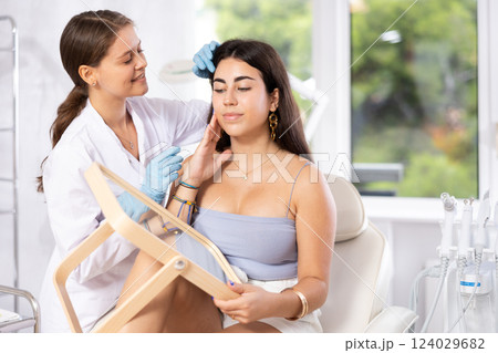 Aesthetician giving professional advice before facial skin treatments to young brunette Aesthetician giving professional advice before facial skin treatments to young brunette 124029682