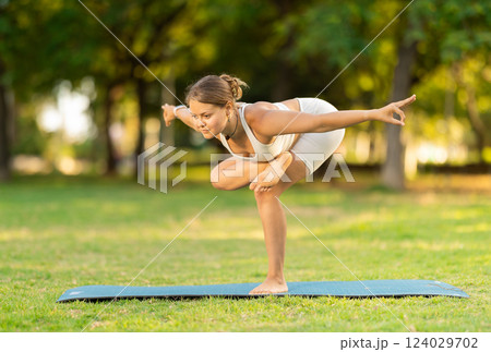 Girl in park on green grass of lawn performs Garudasana Girl in park on green grass of lawn performs Garudasana 124029702
