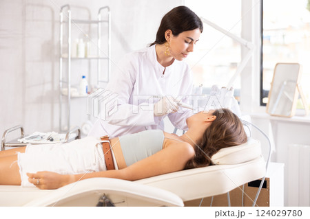 female doctor making facial beauty procedure with leather knife attachment 124029780