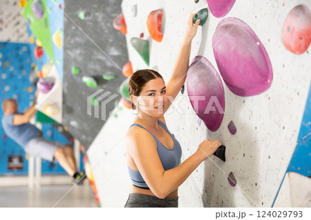Smiling sporty young girl climbing on artificial bouldering wall Smiling sporty young girl climbing on artificial bouldering wall 124029793